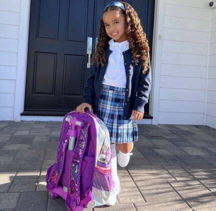 In the images, the little girl appears ready for her first day of school, wearing a blue plaid skirt that matches her hair band and a holographic lilac backpack. (Photo: Instagram release)