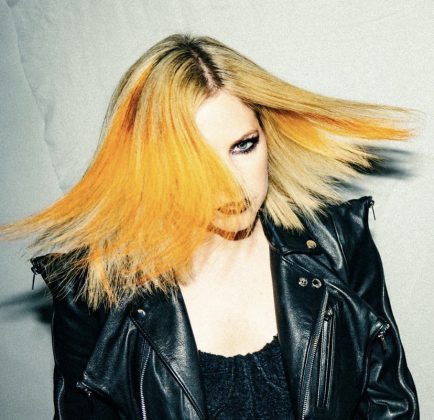 n the video, Lavigne appears seated excitedly and surprised as the British rocker mercilessly cuts off large locks of hair. (Photo: Instagram release)